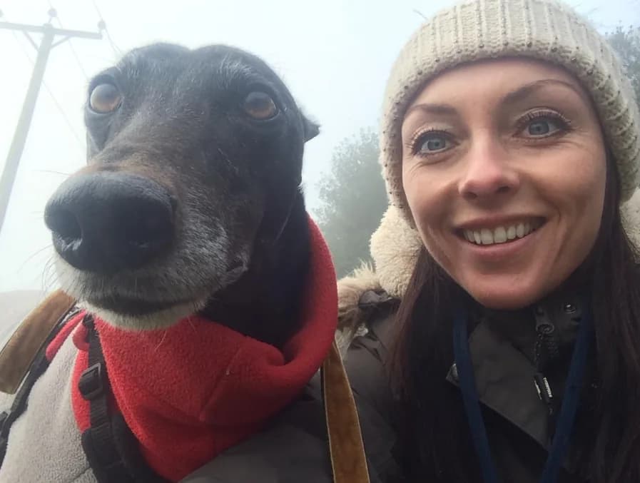 Lorraine smiling on a foggy walk with a greyhound